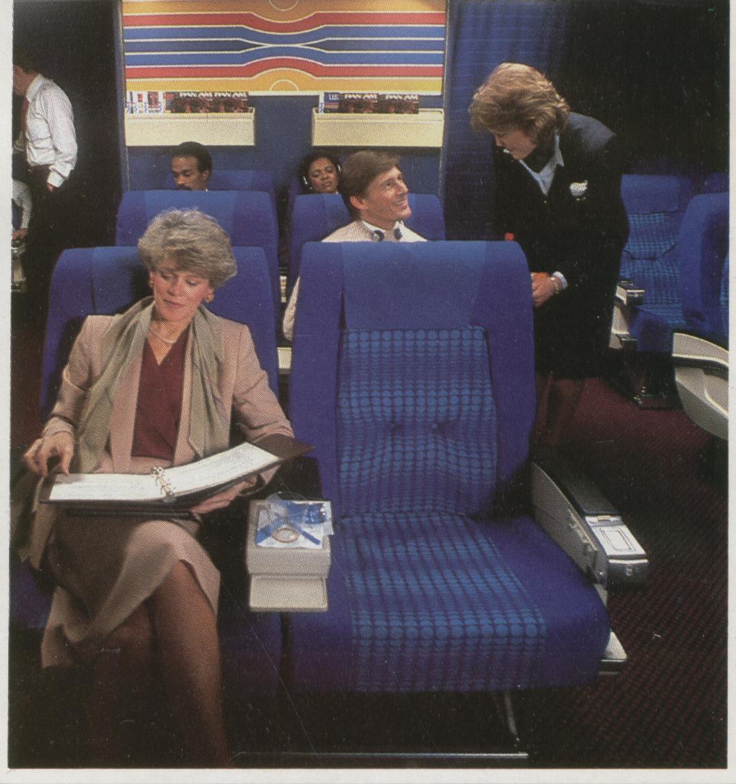1985 When Pan Am converted the Clipper Class (Business Class) cabin from 8 across to 6 across seating bright blue seat covers were adopted as seen in this photo.  In 1988 Pan Am converted the business class  seat covers to a more demure herringbone pattern.